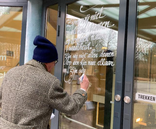 Kalligraaf schrijft gedicht op glazen deur van het gemeentehuis